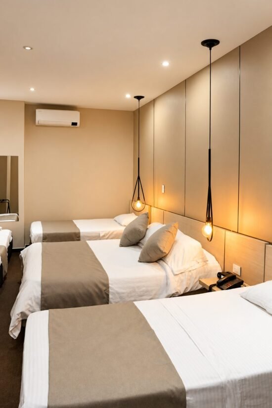 Habitación renovada para tres personas con lámparas colgantes en Hotel BGA Bucaramanga