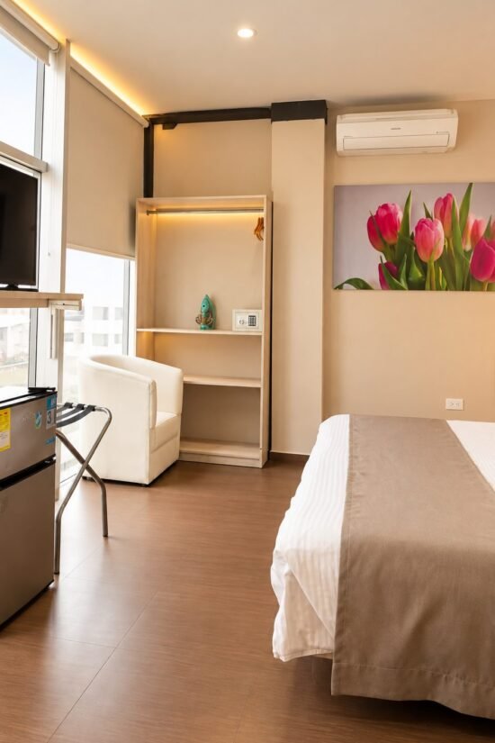 Habitación renovada con cama doble, televisor y ventanal en Hotel BGA Bucaramanga